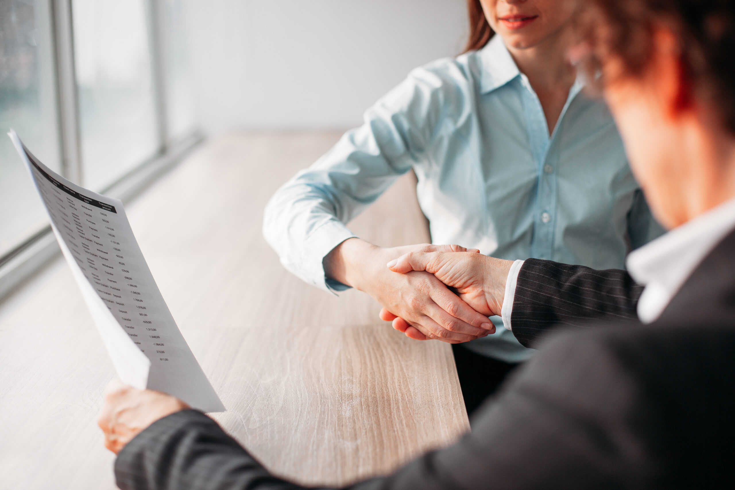 Female professionals celebrating contract signing with handshake