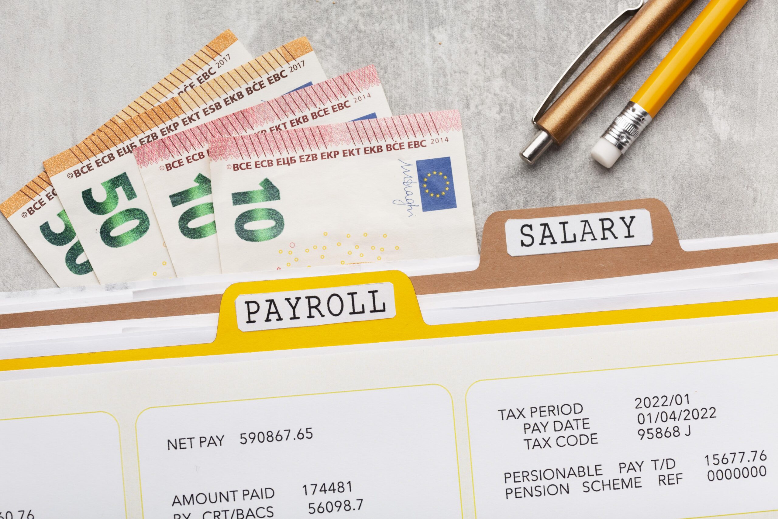 Top-view payroll concept with salary documents, calculator, and cash on a desk.